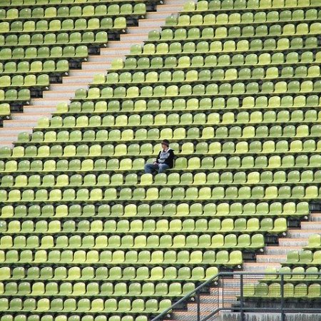 Olympic stadium with only one man sitting down on the seats