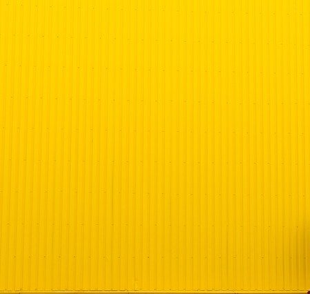 A yellow wall with a lady walking past it