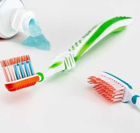 Toothbrushes lying next to a leaking tube of toothpaste
