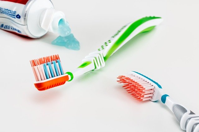 Toothbrushes lying next to a leaking tube of toothpaste