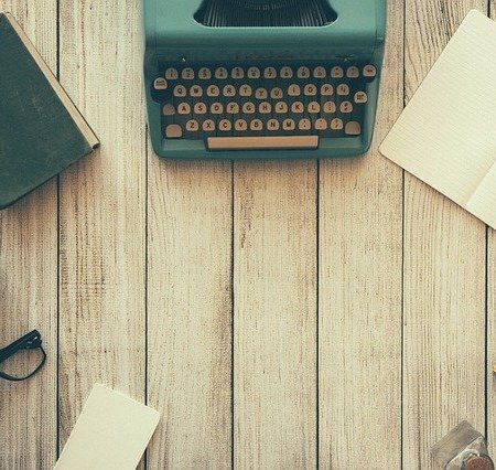 Writing equipment on a desk, including an old fashioned type writer.