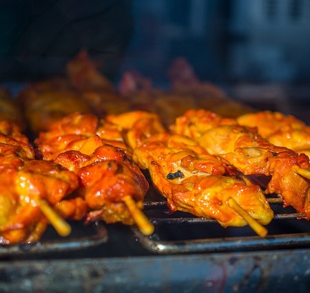 A chicken kebab on a grill cooking