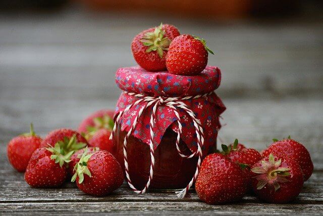 Strawberries around a jar of jam