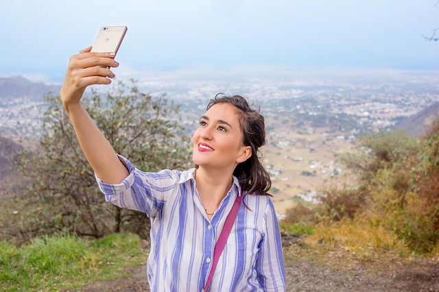 A woman taking a selfie with scenery in the background