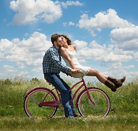 Good looking happy young couple cycling in a field
