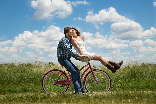 Good looking happy young couple cycling in a field