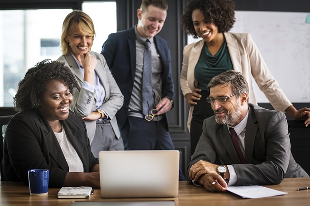 People in a meeting lookig happy staring at a laptop