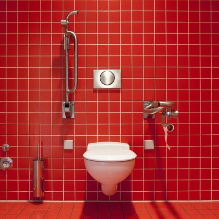 A toilet with a red background of tiles