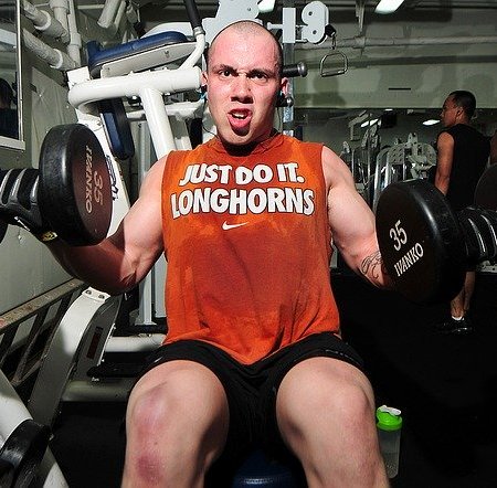 Bald man working out lifting weights in the gym