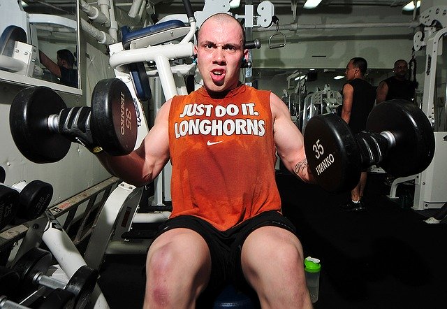Bald man working out lifting weights in the gym