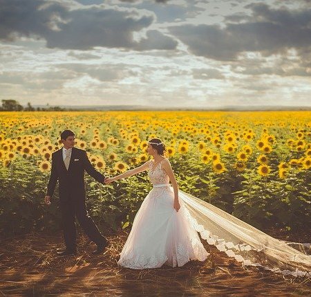 A bride and groom walking in a field of sunflowers