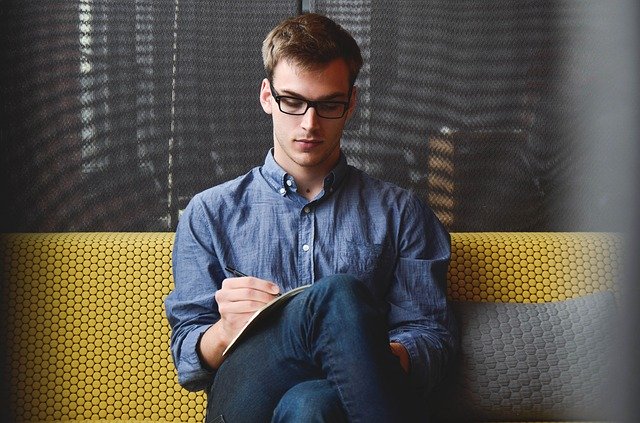 A man sitting on a yellow sofa working