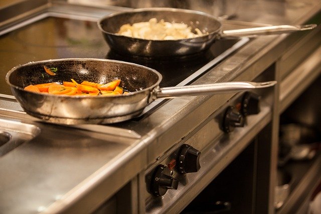 Frying pans in a kitchen cooking food