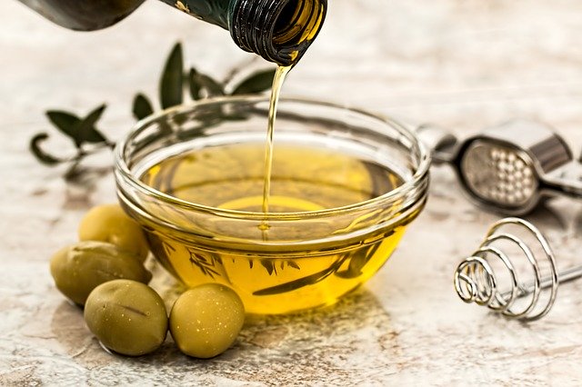 Olive oil being poured into a glass cup