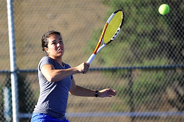 A female tennis playing hitting a ball