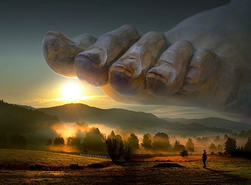 A giant foot with toenails about to stamp on idyllic countryside