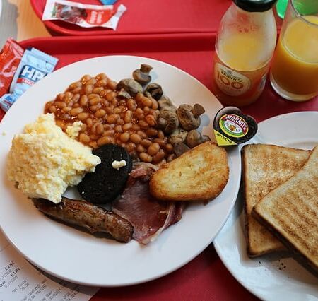 A full English breakfast with baked beans, toast, a sausage, hash brown, and mash.