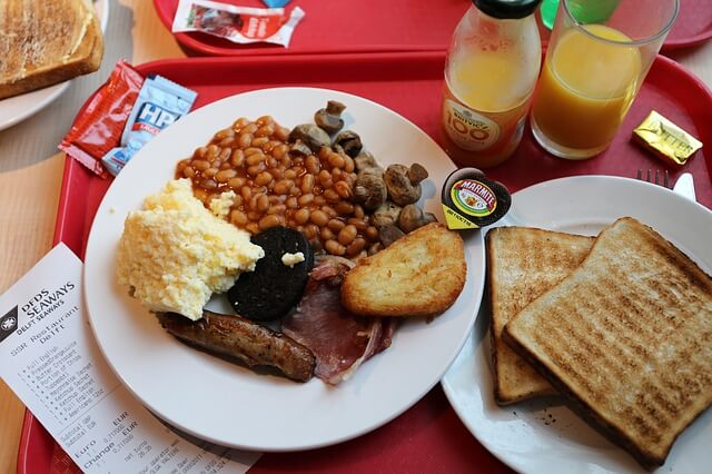 A full English breakfast with baked beans, toast, a sausage, hash brown, and mash.