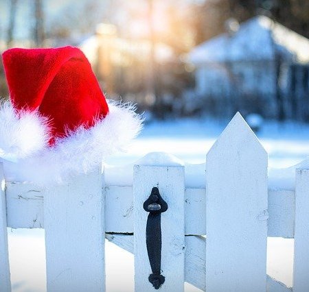 A Santa hat on a picket fence line in the snow.