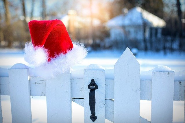 A Santa hat on a picket fence line in the snow.
