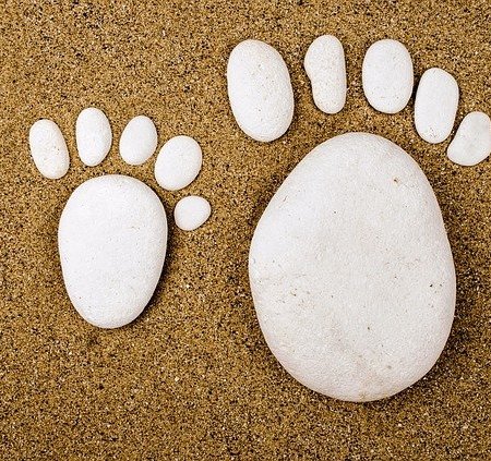 Human feet made out in the shape of rocks on a sandy beach