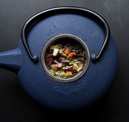 A blue teapot with herbal tea in its centre