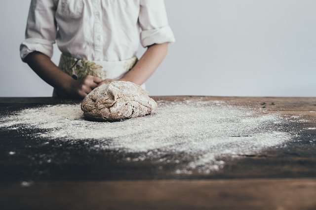 A baker standing near to a fresh mound of dough