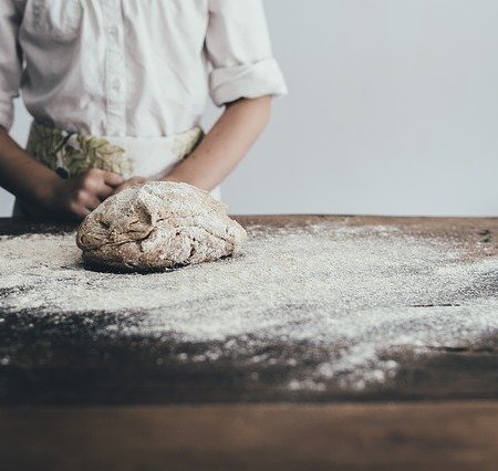 A baker standing near to a fresh mound of dough