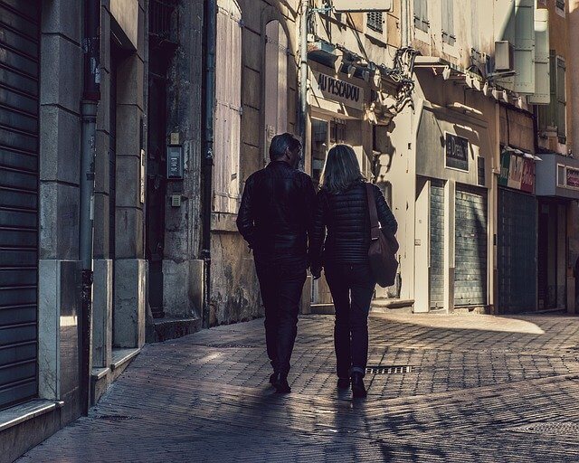 A couple walking on a cobbled street holding hands