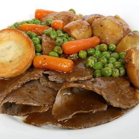 A roast dinner with beef, gravy, roast potatoes, veg, and a Yorkshire pudding