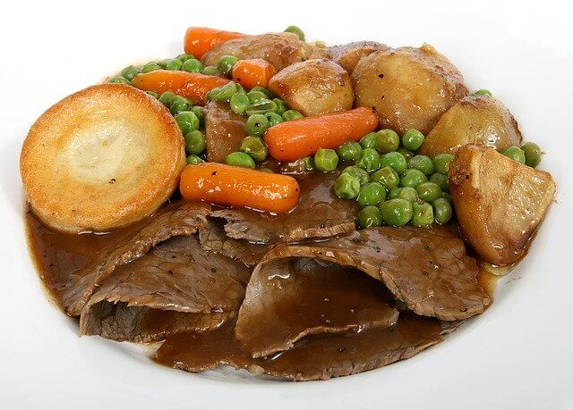 A roast dinner with beef, gravy, roast potatoes, veg, and a Yorkshire pudding