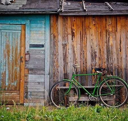 A run down shed with a green bike next to it