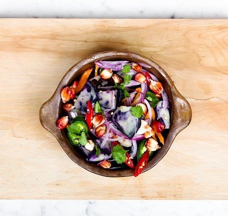 A bowl of salad resting on a chopping board