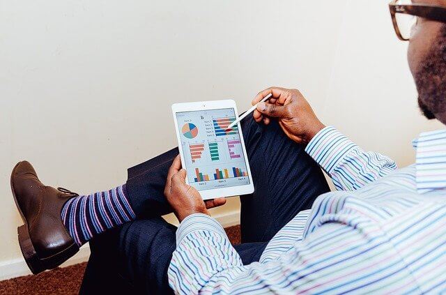 A man pointing at a spreadsheet on his device wearing bright socks with shoes