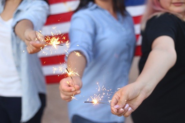 Employees holding indoor sparklers near the American flag