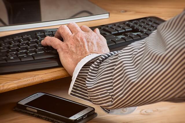 One hand typing on a keyboard whilst the other hand drums on the desk