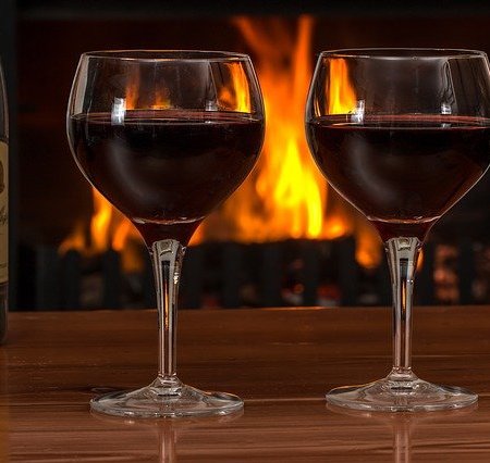 Two glasses of red wine near to a fireplace
